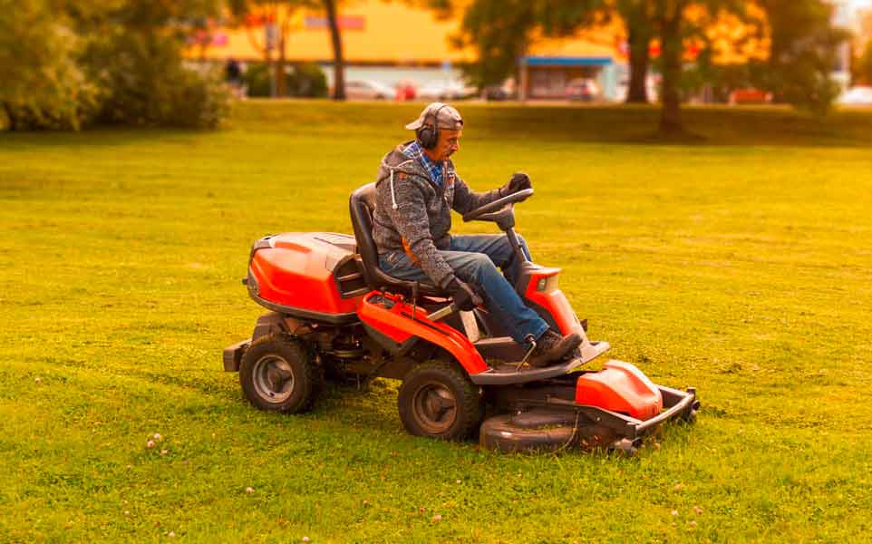 Mann auf rotem Rasenmäher-Traktor